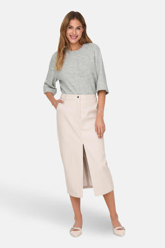 Sweat gris à col rond de ONLY, associé à une jupe crème avec échancrure et des escarpins.