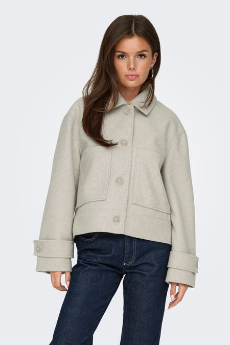 Manteau court écru d'ONLY, avec des manches longues et associé à des jeans foncés.