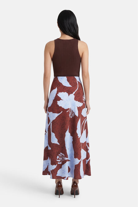Lange, veelkleurige rok van ONLY, met bruine achtergrond en blauwe bloemenprint, gezien van achteren.