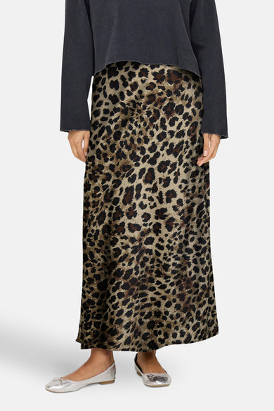 Bruine lange rok van ONLY®, met een luipaardprint, gecombineerd met een donkergrijs shirt en zilveren ballerina's.
