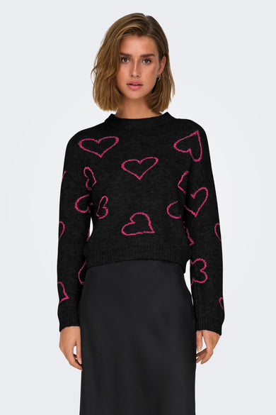 Pull-over noir à col rond de ONLY, avec un motif de cœurs roses, associé à une longue jupe noire et des bottes.