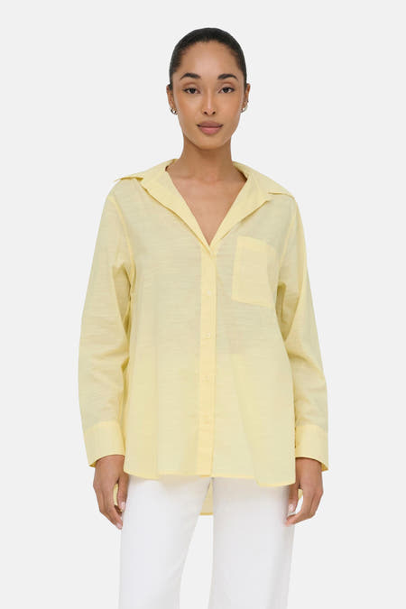 Geel hemd met lange mouwen van ONLY, met een borstzak en witte broek.
