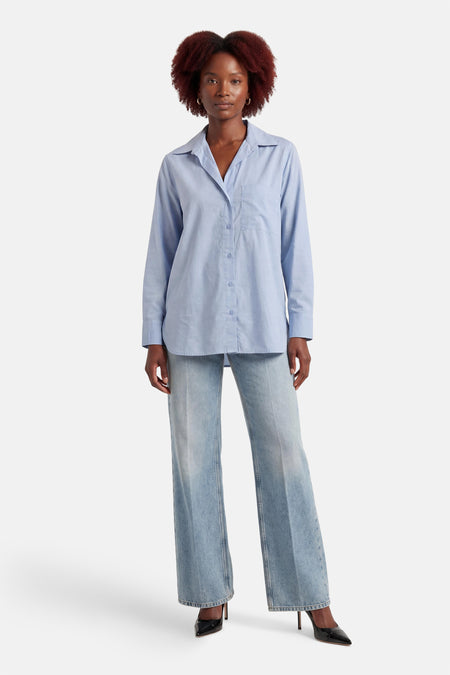 Blauw overhemd met lange mouwen van ONLY, met knoopsluiting en een borstzak, gecombineerd met wijde jeans en zwarte pumps.
