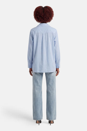 Blauw hemd met lange mouwen van ONLY, gezien van achteren, gedragen met wijde jeans en hakken.
