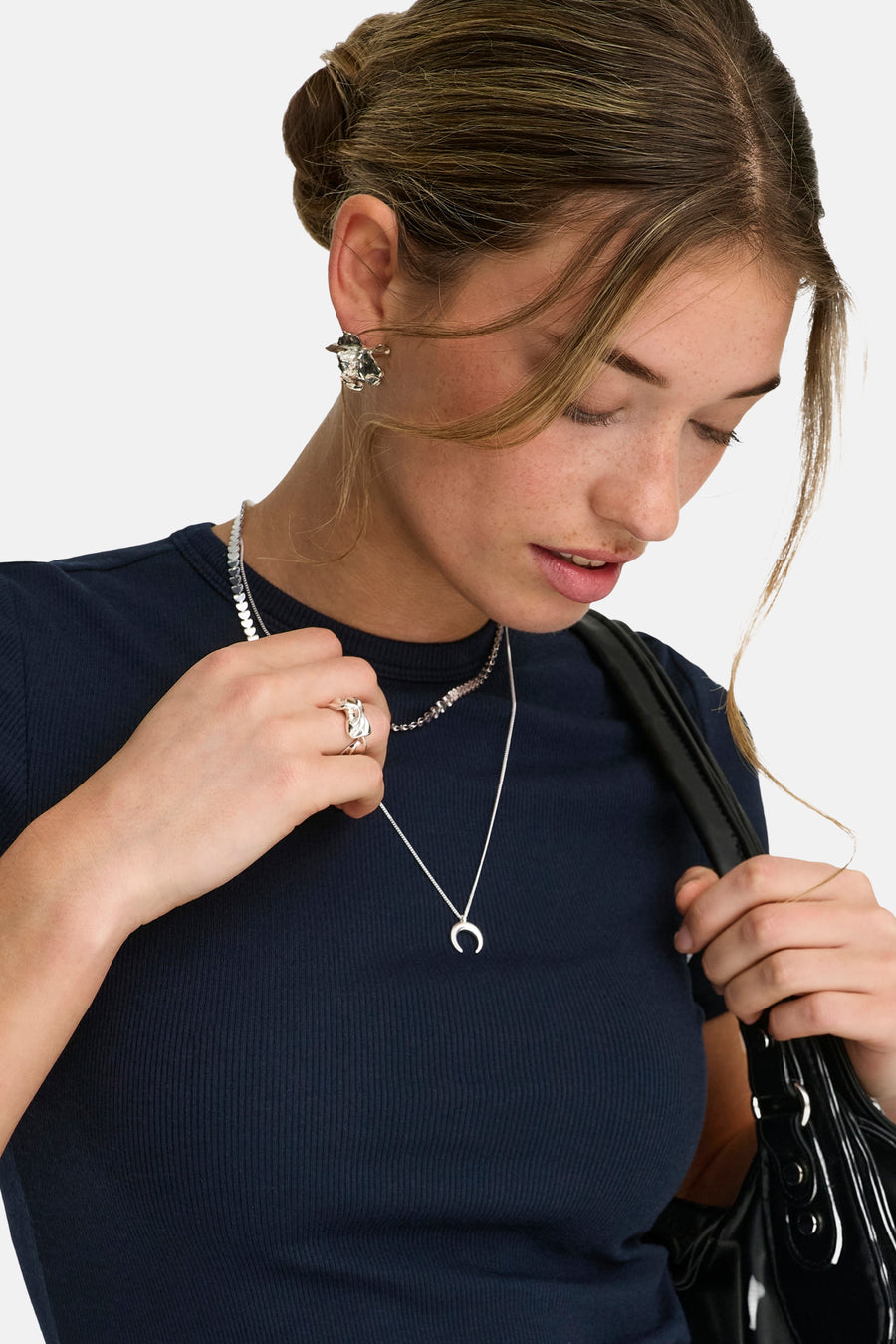 Blauw T-shirt met korte mouwen van ONLY®, geribbeld, gedragen met zilveren sieraden en een zwarte tas.
