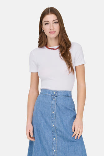 T-shirt blanc à manches courtes de ONLY, porté avec une jupe bleue et un collier rouge.