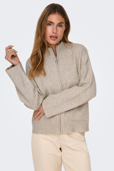 Ecru gilet van JDY, met een ritssluiting aan de voorkant en gedragen over een beige broek.