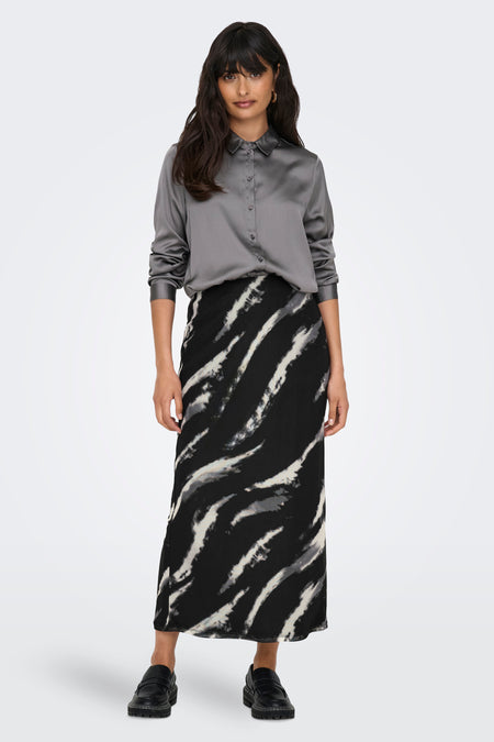Grijze rok van ONLY, met een zwart-wit gestreept patroon, gecombineerd met een grijze satijnen blouse en zwarte schoenen.

