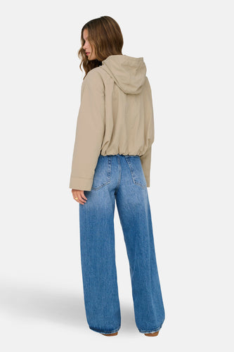 Beige jas van ONLY, gezien van achteren, met een capuchon en wijde jeans.
