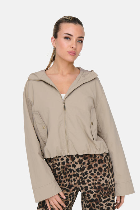 Beige korte jas van ONLY, met lange mouwen en een luipaardprint broek.
