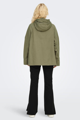 Achterkant van een vrouw in een olijfgroene jas met capuchon en zwarte broek.