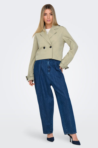 Beige korte jas van ONLY met dubbele knoopsluiting, gedragen met een jeans met hoge taille.
