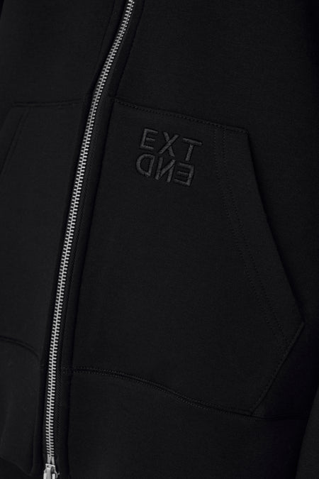 Zwarte sweater met capuchon van ONLY® met zilveren rits en geborduurd EXTEND-logo op borstzakje, close-up detail