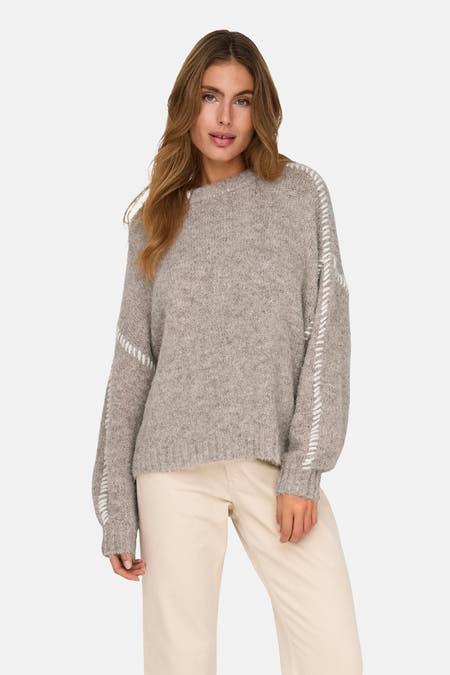 Beige ronde hals trui van JDY, met witte stiksels op de mouwen, gedragen met een crèmekleurige broek.
