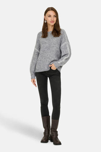 Sweat-shirt gris à col rond de JDY, avec des boutons sur les manches, associé à des jeans noirs et des bottes marron.