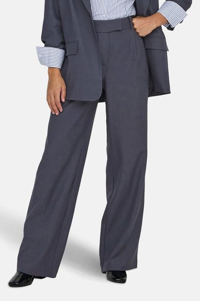 Pantalon de costume bleu ONLY, avec des jambes larges et porté avec un chemisier rayé.