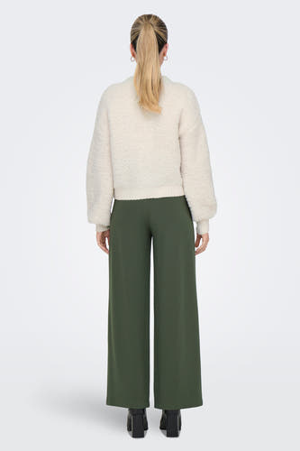 Cardigan écru de JDY, avec des manches longues, associé à une jupe verte et des chaussures noires.