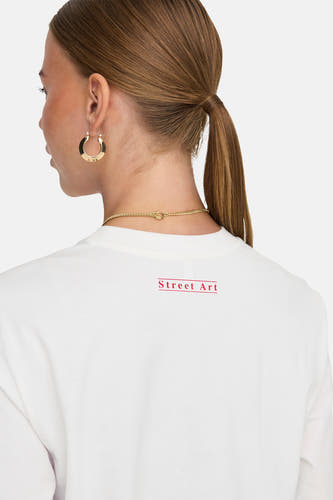 Wit T-shirt met korte mouwen van ONLY, met rode tekst op de rug en gouden sieraden.

