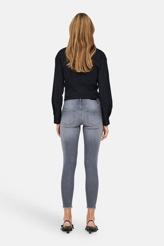 Jean skinny bleu moyen ONLY avec un zoom brut et une blouse à rayures noires.
