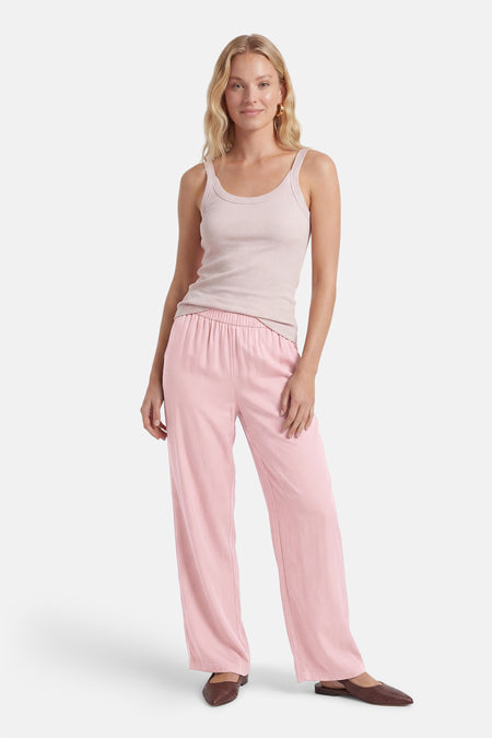Roze broek van ONLY® met wijde pijpen en elastische tailleband, gedragen met een lichtroze top en bruine schoenen.