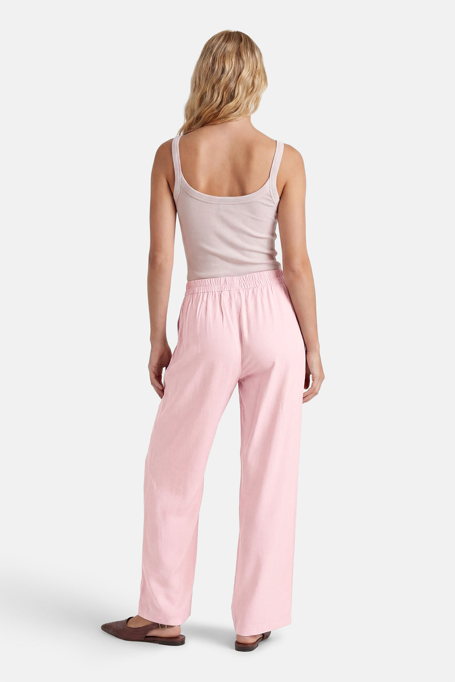 Roze broek van ONLY met wijde pijpen en elastische taille, gedragen door een model met lichtroze top en bruine sandalen, achteraanzicht.