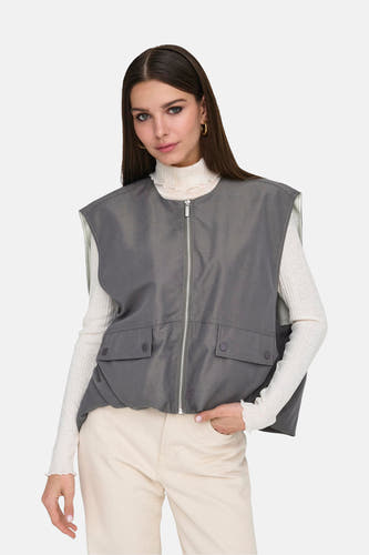 Grijze bodywarmer van ONLY®, met ritssluiting en zakken, gedragen over een witte coltrui en beige broek.