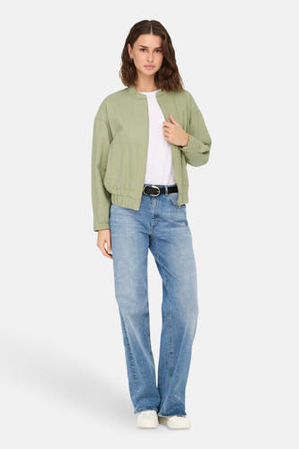 Groene jas van ONLY, gedragen over een wit T-shirt en een blauwe jeans met een zwarte riem.
