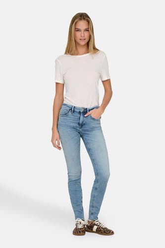Lichtblauwe skinny jeans van ONLY, met lichte wassing en gecombineerd met een wit T-shirt en sneakers met dierenprint.
