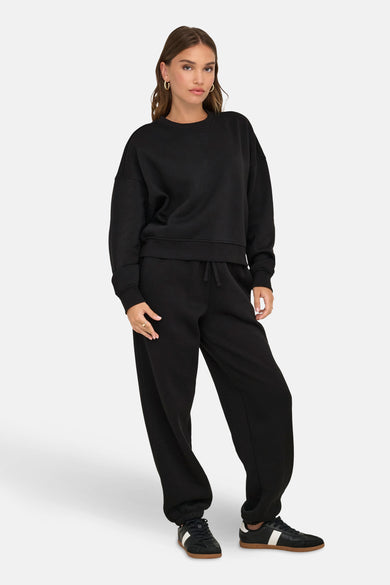 Zwarte sweater van ONLY, gedragen met een bijpassende joggingbroek en zwarte sneakers.

