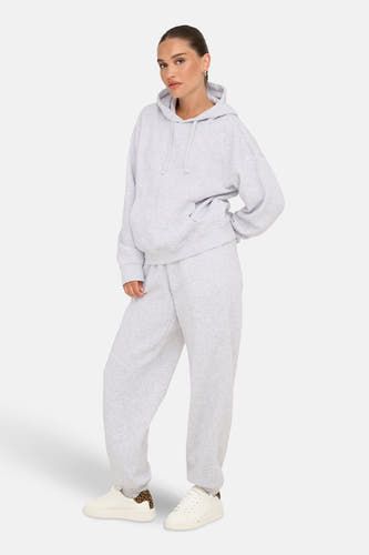 Pull-over gris avec capuche ONLY, avec des manches longues et une coupe décontractée, porté avec un pantalon de jogging et des baskets.