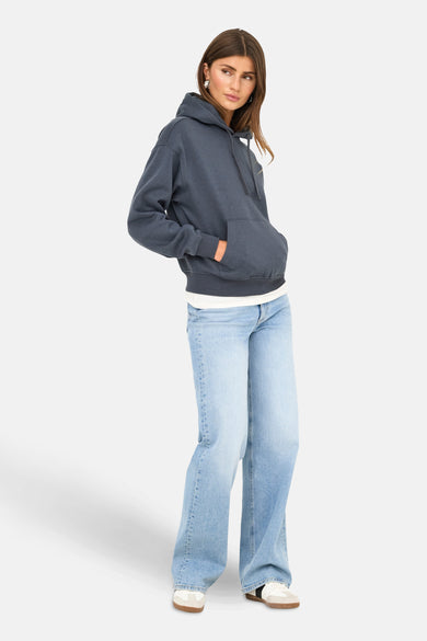 Blauwe sweater met kap van ONLY, gedragen met wijde jeans en witte sneakers.
