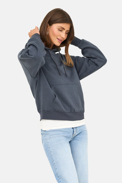 Blauwe sweater met kap van ONLY, met trekkoord, kangoeroezak en gecombineerd met een wit T-shirt en jeans.
