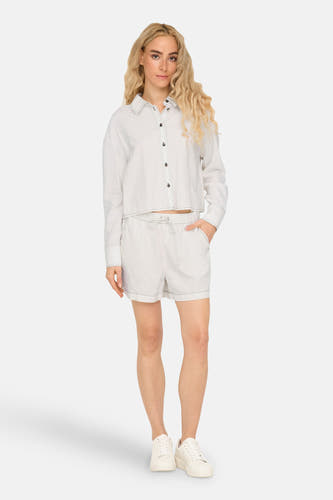 Chemise blanche à manches longues de ONLY, avec des coutures contrastantes, portée avec des short blancs et des baskets.