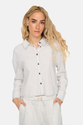 Chemise à manches longues blanche ONLY® avec des boutons et des glands noirs, portée avec un pantalon à cece.