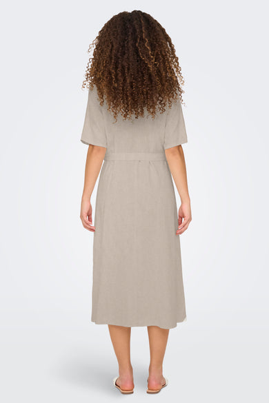 Beige kleedje met korte mouwen van JDY, gezien van achteren, met een ceintuur en krullend haar.
