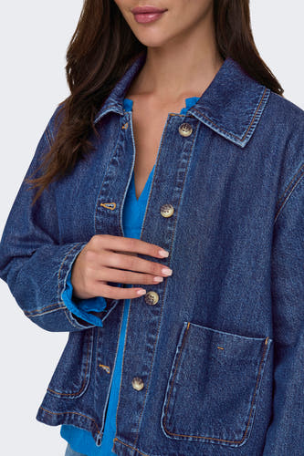 Donkerblauwe jeansjas van ONLY®, met knoopsluiting en zakken, gedragen over een blauwe top.
