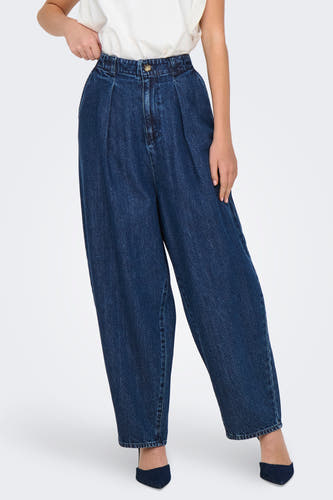 Donkerblauwe wijde jeans van ONLY, met plooien en gedragen met een witte top en blauwe pumps.
