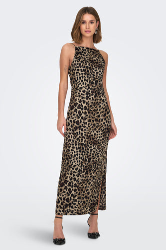 Vrouw in lange luipaardjurk met zwarte hakken staand voor witte achtergrond.