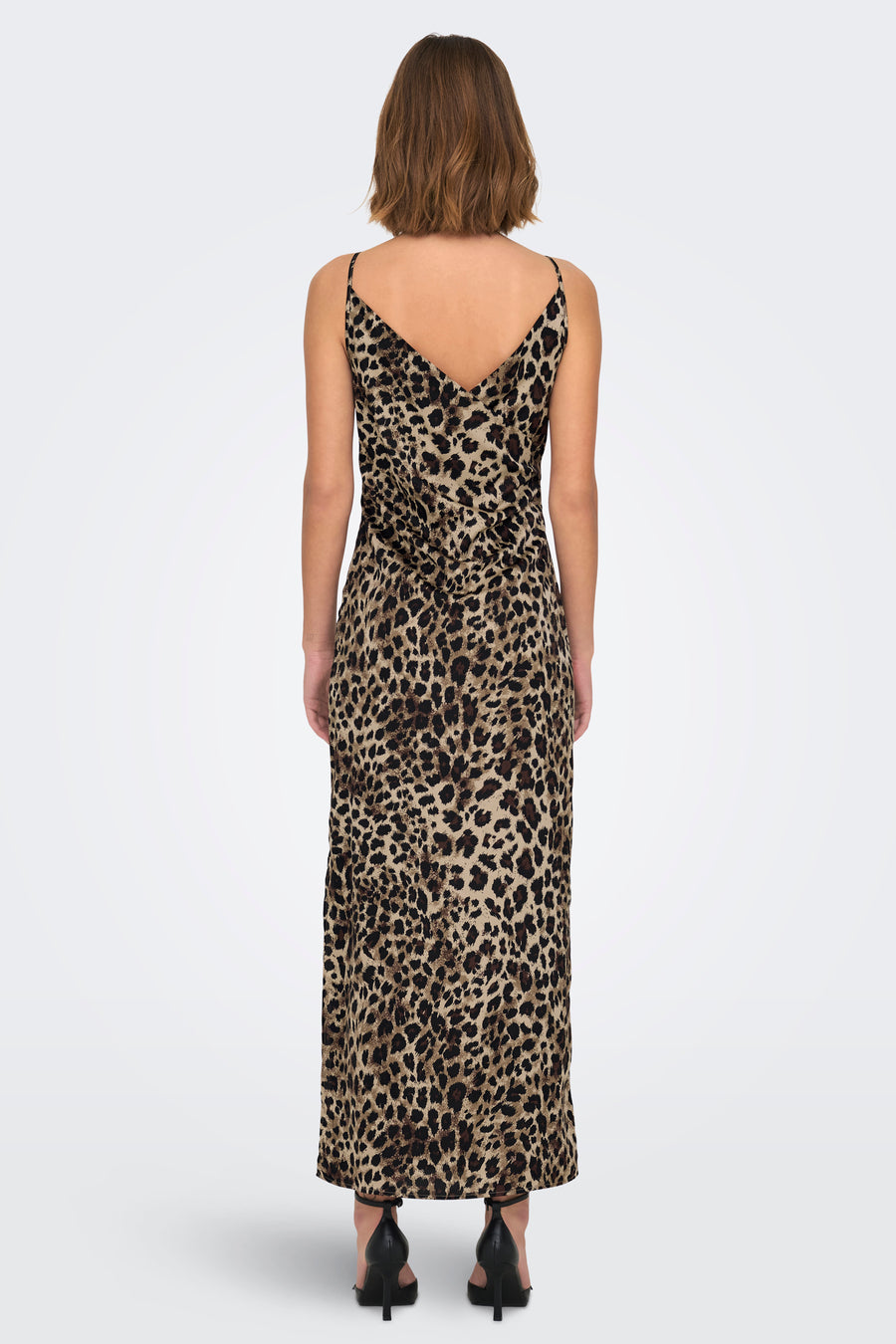 Achterkant van een vrouw in een luipaardjurk met zwarte hakken.