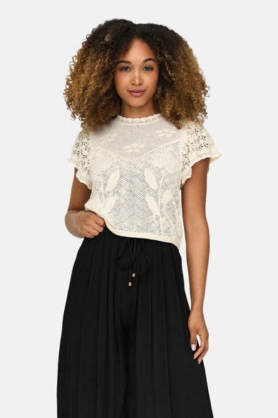Ecru trui van ONLY met openwork details, gedragen met een zwarte broek met trekkoord.
