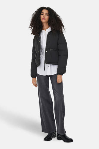 Manteau court noir de JDY, porté avec un chemisier blanc, des jeans larges et des bottines noires.