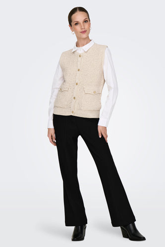 Ecrukleurige gilet van ONLY, gedragen over een wit overhemd en gecombineerd met zwarte broeken en hakken.
