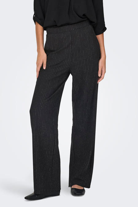 Zwarte broek van JDY met krijtstreep en wijde pijpen, gecombineerd met een zwarte blouse en platte schoenen.
