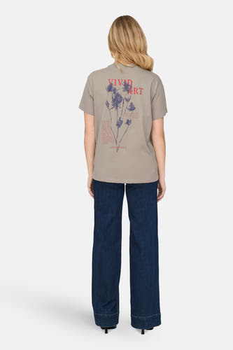 Beige T-shirt met korte mouwen van ONLY, met rode en blauwe opdruk op de rug, gecombineerd met donkere jeans.
