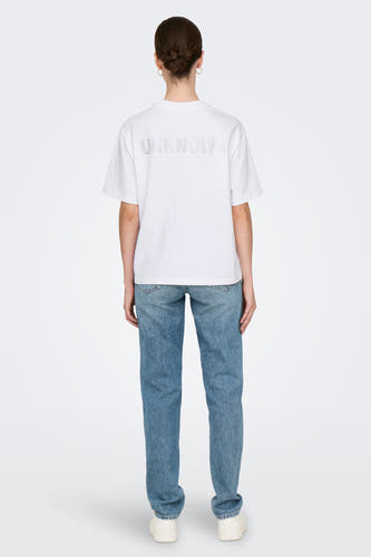 T-shirt blanc à manches courtes de ONLY, avec des lettres ornées de strass sur le dos, associé à des jeans et des baskets blanches.