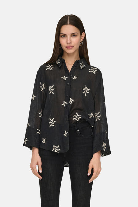 Zwart, lange mouwen hemd van JDY, met geborduurde details en gedragen met een zwarte jeans.
