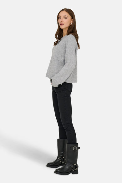 Grijze cardigan van ONLY, met zakken, gecombineerd met zwarte jeans en zwarte laarzen.
