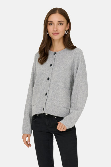 Grijze cardigan van ONLY, met zwarte knopen en opgestikte zakken, gedragen met een zwarte jeans.
