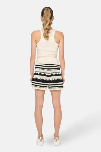 Crème court ONLY, avec un motif à rayures noires et porté avec un t-shirt blanc et des baskets blanches.