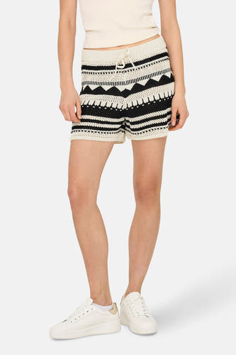 Crème court ONLY, avec un motif tricoté et une ceinture à la taille, porté avec un haut blanc et des baskets blanches.